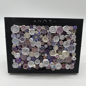 Black studded frame filled with rolled magazines created by Trash Art Treasures